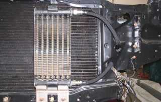 oilcoolerlocation54 Close-up of car radiator and cooling system pipes.
